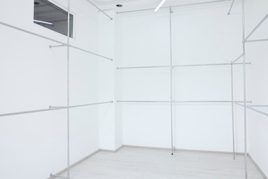 Empty room with beautiful white walls and garment racks during repair