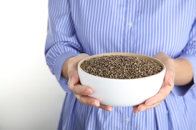 Woman holding bowl with hemp seeds on white background, closeup