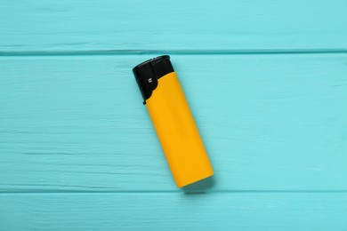 Photo of Stylish small pocket lighter on turquoise wooden background, top view