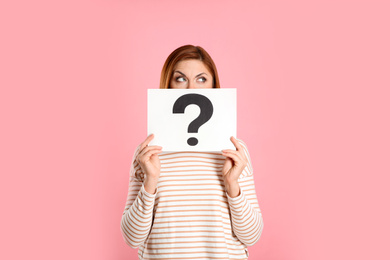 Photo of Confused woman holding question mark sign on pink background