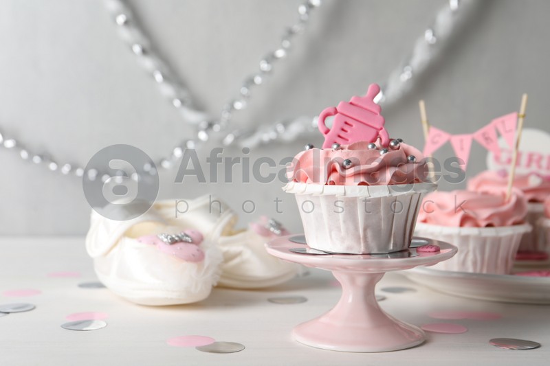 Photo of Delicious cupcake with pink cream and topper on white wooden table, space for text. Baby shower party