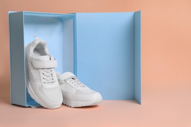 Pair of comfortable sports shoes and box on pale coral background. Space for text