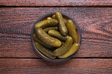 Plate with pickled cucumbers on wooden table, top view