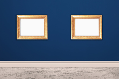 Frames with empty canvases on blue wall in modern art gallery. Space for design
