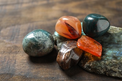 Photo of Different beautiful gemstones on wooden table, closeup