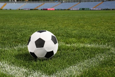 Football ball on green field grass in stadium