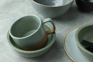 Stylish empty dishware and cup on light grey table, closeup