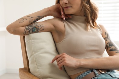 Photo of Beautiful woman with tattoos on arms resting at home, closeup