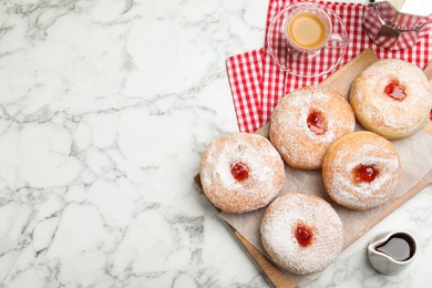 Delicious jam donuts served with coffee on white marble table, flat lay. Space for text