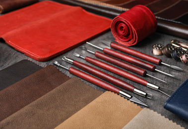 Leather samples and craftsman tools on grey stone background