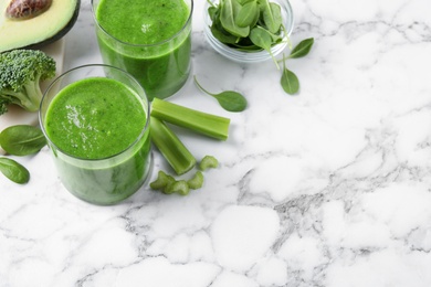 Delicious green juice and fresh ingredients on white marble table, above view. Space for text