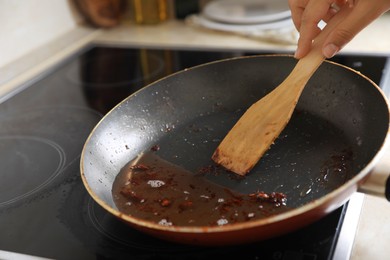 Woman holding spatula and frying pan with used cooking oil, closeup