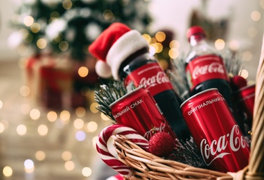 MYKOLAIV, UKRAINE - January 01, 2021: Basket with Coca-Cola drinks against blurred Christmas lights, closeup