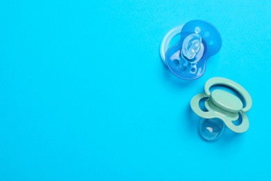 Photo of Flat lay composition with pacifiers and other baby stuff on light blue background. Space for text