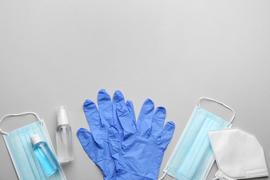 Flat lay composition with medical gloves, masks and hand sanitizers on grey background. Space for text