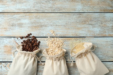 Photo of Cotton eco bags with cereals and coffee beans on wooden table, flat lay. Space for text