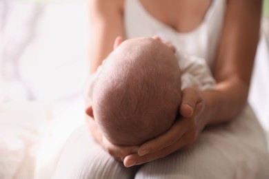 Photo of Mother holding newborn baby indoors, focus on head