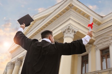 Photo of Student with diploma after graduation ceremony outdoors, low angle view