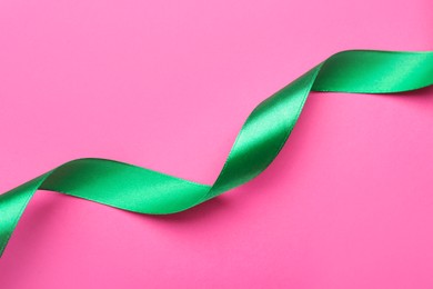 Beautiful ribbon on pink background, top view