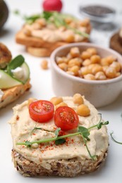 Delicious sandwiches with hummus and ingredients on white table