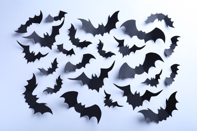 Many black paper bats on white background, flat lay. Halloween decor