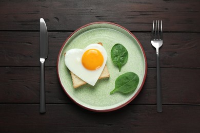 Photo of Tasty breakfast with heart shaped fried egg served on wooden table, flat lay
