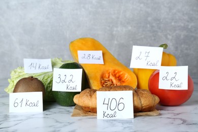 Food products with calorific value tags on white marble table. Weight loss concept