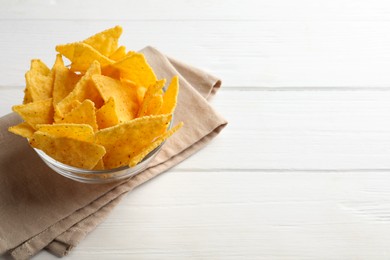 Photo of Tortilla chips (nachos) in bowl on white wooden table. Space for text