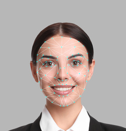 Facial recognition system. Young woman with biometric identification scanning grid on grey background