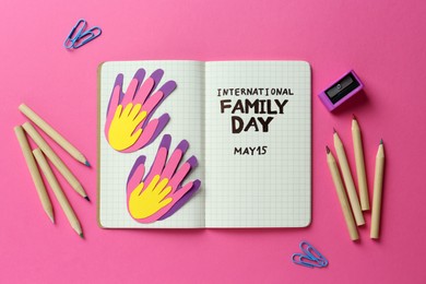 Notebook with text International Family Day May 15 and stationery on pink background, flat lay