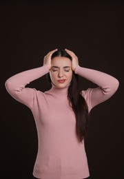 Young woman suffering from headache on dark background. Cold symptoms
