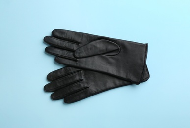 Pair of stylish leather gloves on light blue background, flat lay