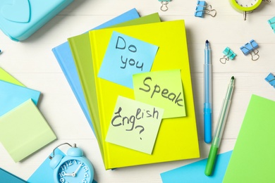 Question DO YOU SPEAK ENGLISH? and stationery on white wooden background, flat lay