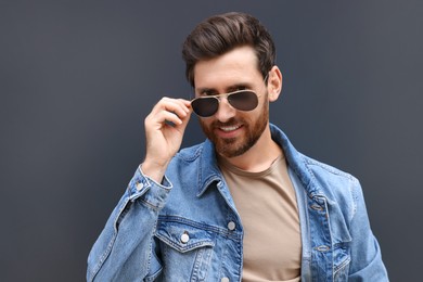 Photo of Portrait of handsome bearded man with sunglasses on grey background