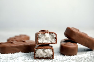 Delicious milk chocolate candy bars with coconut filling on grey table, closeup. Space for text