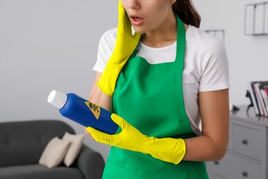 Photo of Woman looking at bottle of toxic household chemical with warning sign, closeup