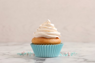 Delicious cupcake decorated with cream on white marble table
