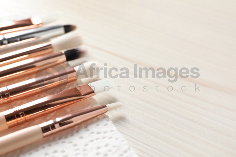 Set of different makeup brushes drying after cleaning on white wooden table, closeup. Space for text