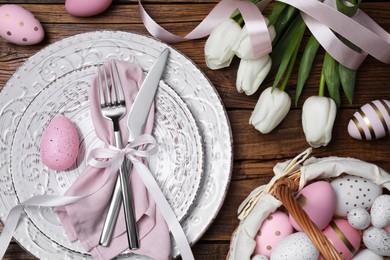 Photo of Festive table setting with painted eggs and tulips, flat lay. Easter celebration