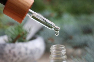 Dripping pine essential oil into bottle, closeup