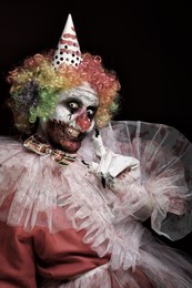 Terrifying clown on dark background. Halloween party costume