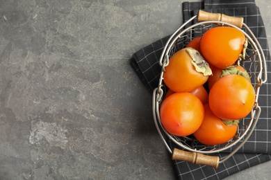 Delicious fresh persimmons on grey table, flat lay. Space for text