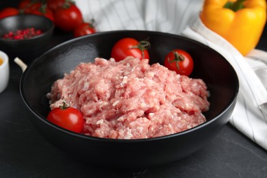 Raw chicken minced meat with tomatoes on black table, closeup