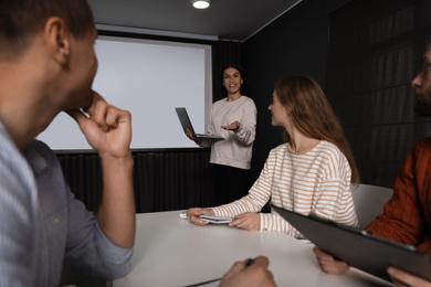 Business people listening to speaker in conference room with video projection screen