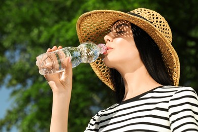 Beautiful young woman drinking water outdoors. Refreshing drink