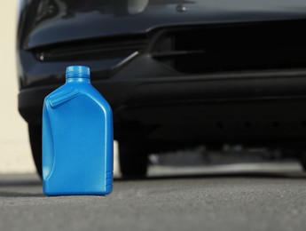 Photo of Blue canister with motor oil near car on asphalt road