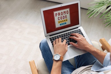 Photo of Man holding laptop with activated promo code indoors, above view