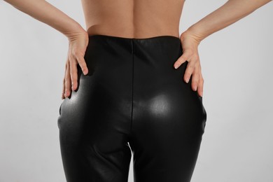Woman in sexy black leather pants on light background, closeup