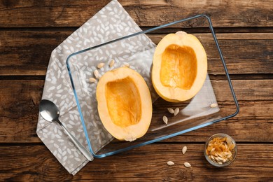 Halves of fresh spaghetti squash in baking dish on wooden table, flat lay. Cooking at home