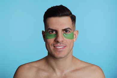 Man with green under eye patches on light blue background